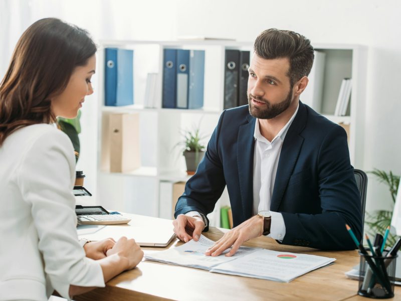 handsome advisor discussing document with investor at workspace